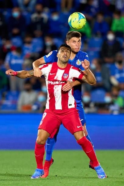Jorge Cuenca of Getafe battles for the ball with Luis Suarez of Atletico de Madrid during the La Liga Santander match between Getafe CF and Club...