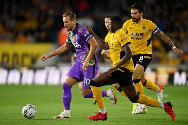 Harry Kane of Tottenham Hotspur runs with the ball whilst under pressure from Yerson Mosquera and Ruben Neves of Wolverhampton Wanderers during the...