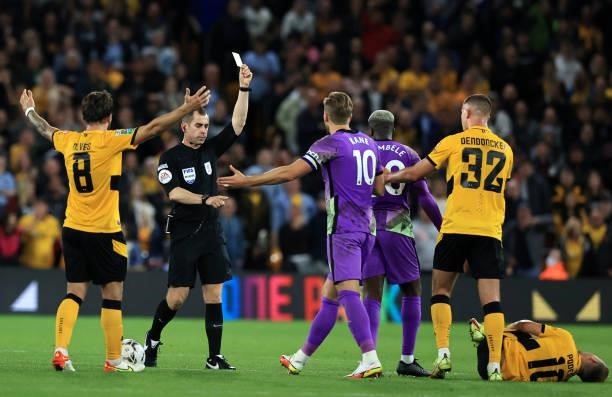 Match Referee, Peter Bankes shows a yellow card to Tanguy Ndombele of Tottenham Hotspur after fouling Daniel Podence of Wolverhampton Wanderers...