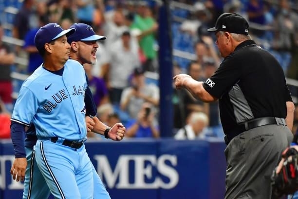 Charlie Montoyo holds Pete Walker of the Toronto Blue Jays back as umpire Joe West approaches during the eighth inning after Ryan Borucki hit Kevin...