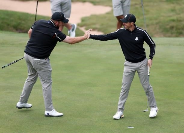 Shane Lowry of Ireland and team Europe and Rory McIlroy of Northern Ireland and team Europe celebrate on the ninth green during practice rounds prior...