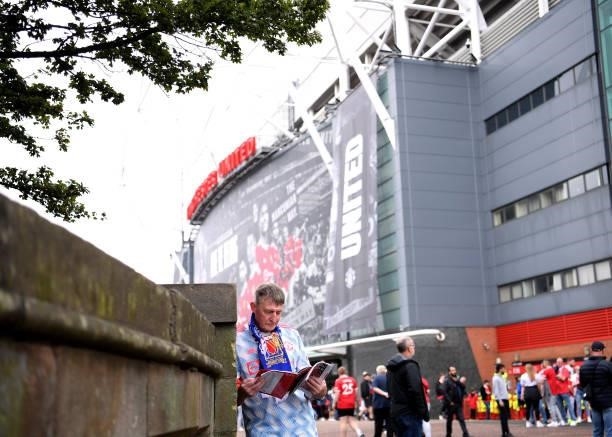 Manchester United fan reads a matchday programme prior to the Premier League match between Manchester United and Aston Villa at Old Trafford on...