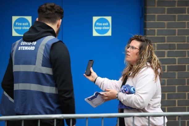 Fan shows a steward evidence of her negative COVID-19 test prior to the Premier League match between Chelsea and Manchester City at Stamford Bridge...