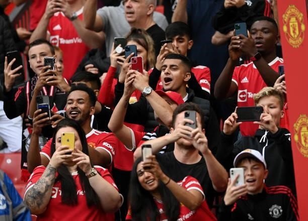 Fans take photos with their phones during the Premier League match between Manchester United and Aston Villa at Old Trafford on September 25, 2021 in...