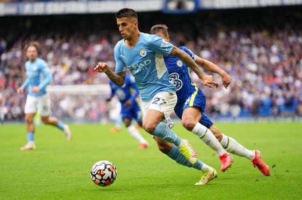 Joao Cancelo of Manchester City runs with the ball whilst under pressure from Cesar Azpilicueta of Chelsea during the Premier League match between...