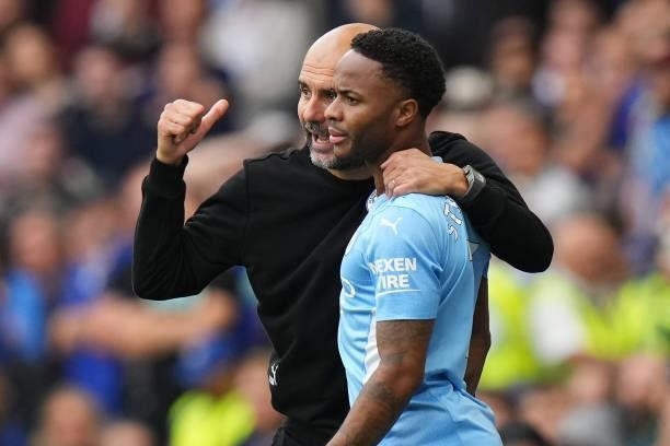 Pep Guardiola, Manager of Manchester City speaks with player Raheem Sterling during the Premier League match between Chelsea and Manchester City at...