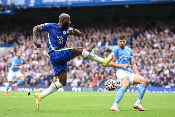 Romelu Lukaku of Chelsea crosses the ball while under pressure from Ruben Dias of Manchester City during the Premier League match between Chelsea and...