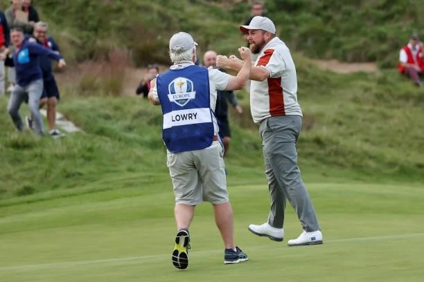 Shane Lowry of Ireland and team Europe celebrates with caddie Bo Martin on the 18th green after winning his match with Tyrrell Hatton of England and...