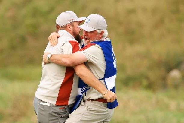 Shane Lowry of Ireland and team Europe celebrates with caddie Bo Martin on the 18th green after winning his match with Tyrrell Hatton of England and...