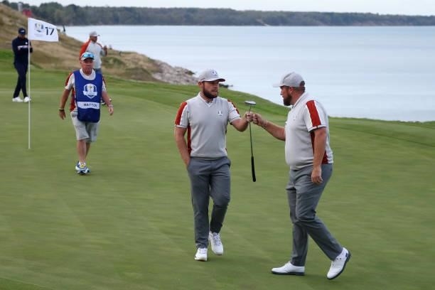 Tyrrell Hatton of England and team Europe and Shane Lowry of Ireland and team Europe bump fists on the 17th green during Saturday Afternoon Fourball...