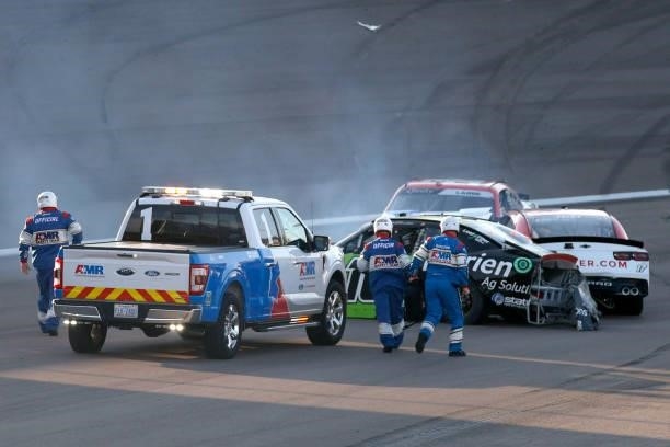 The NASCAR safety crew assist Jeb Burton, driver of the Nutrien Ag Solutions Chevrolet, JJ Yeley, driver of the Parler Chevrolet, and Alex Labbe,...