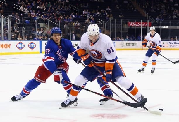 Aatu Raty of the New York Islanders carries the puck against Morgan Barron of the New York Rangers during the first period in a preseason game at...