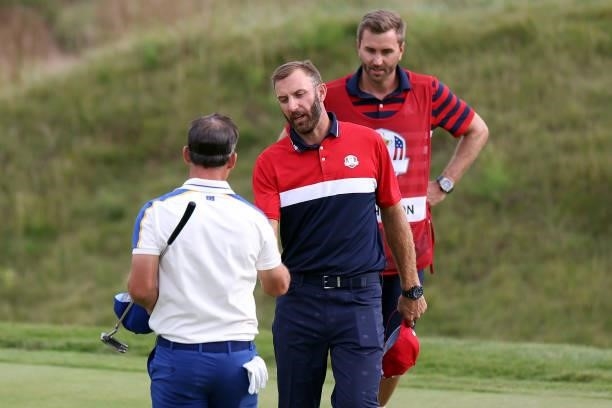 Dustin Johnson of team United States shakes hands with Paul Casey of England and team Europe during Sunday Singles Matches of the 43rd Ryder Cup at...