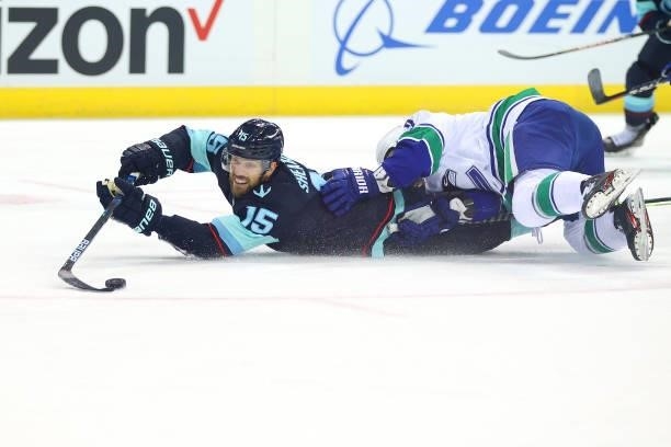 Riley Sheahan of the Seattle Kraken slides for the puck against Tucker Poolman of the Vancouver Canucks during the first period of a preseason game...