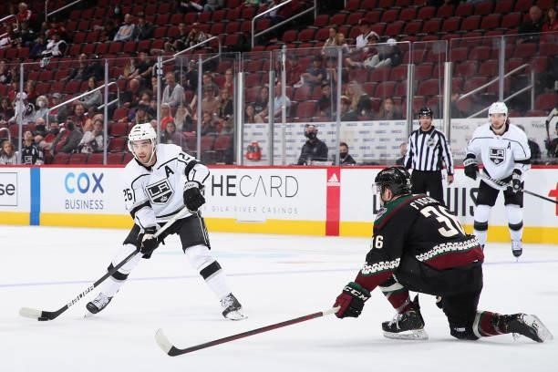 Sean Walker of the Los Angeles Kings looks to pass the puck around Christian Fischer of the Arizona Coyotes during the first period of the preseason...