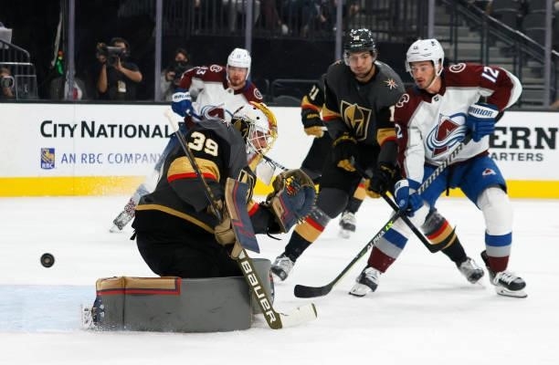 Nicolas Hague of the Vegas Golden Knights and Jayson Megna of the Colorado Avalanche watch a shot by Oskar Olausson of the Avalanche get by Laurent...