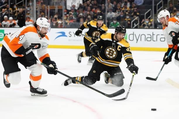 Patrice Bergeron of the Boston Bruins reaches for the puck against Nate Thompson of the Philadelphia Flyers during the first period of the preseason...