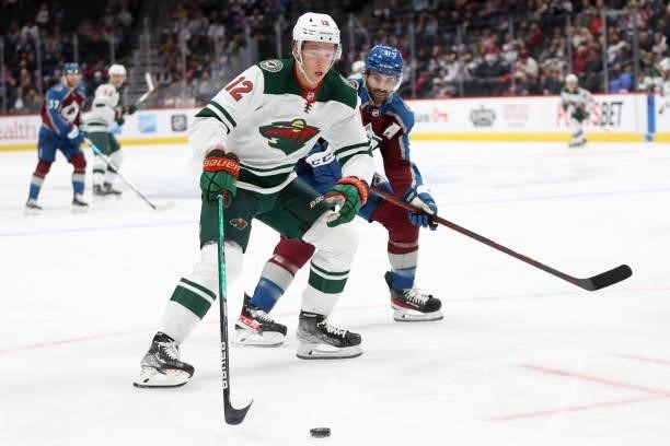 Matthew Boldy of the Minnesota Wild advances the puck the puck against Nazem Kadri of the Colorado Avalanche in the first period at Ball Arena on...