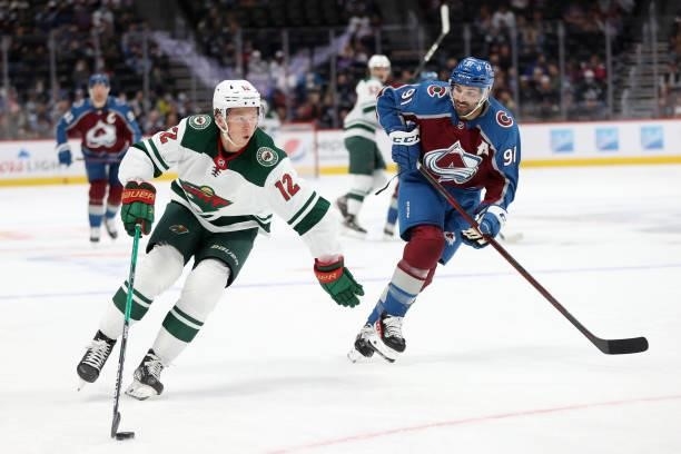 Matthew Boldy of the Minnesota Wild advances the puck the puck against Nazem Kadri of the Colorado Avalanche in the first period at Ball Arena on...