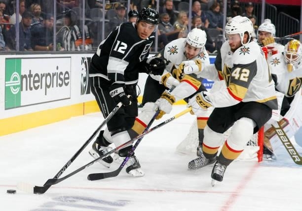 Trevor Moore of the Los Angeles Kings tries to control the puck against Nicolas Hague and Daniil Miormanov of the Vegas Golden Knights in the third...