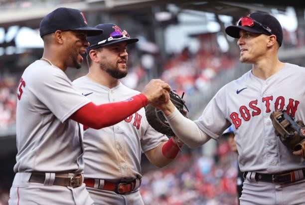 Xander Bogaerts, Kyle Schwarber and Enrique Hernandez of the Boston Red Sox celebrate as they walk off the field against the Washington Nationals at...
