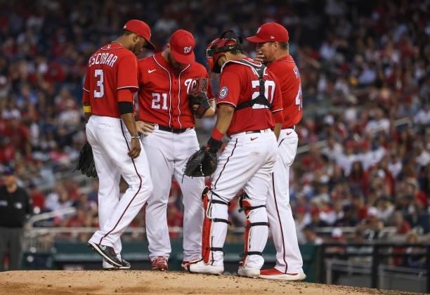 Alcides Escobar, Tanner Rainey, Keibert Ruiz and Jim Hickey of the Washington Nationals talk on the mound in the eighth inning against the Boston Red...