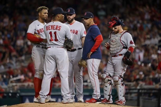 Boston Red Sox manager Alex Cora talks with members of his team as they play the Washington Nationals at Nationals Park on October 02, 2021 in...