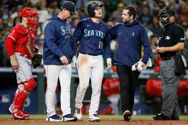 Jarred Kelenic of the Seattle Mariners is checked by medical staff and manager Scott Servais after he was hit by a pitch against the Los Angeles...