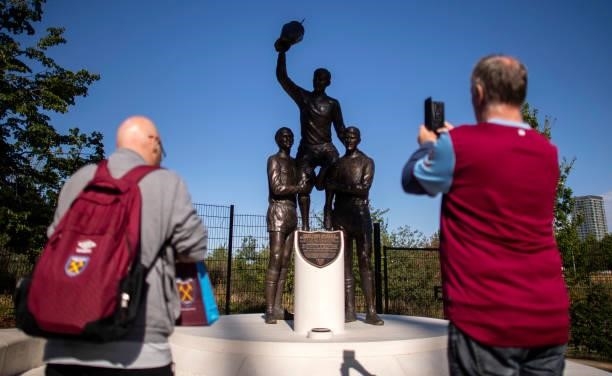 Fans take a photo of a statue of former West Ham United players, Martin Peters, Bobby Moore and Geoff Hurst celebrating winning the 1965 European Cup...