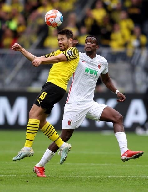 Raphael Guerreiro of Dortmund goes up for a header with Sergio Cordoba of Augsburg during the Bundesliga match between Borussia Dortmund and FC...