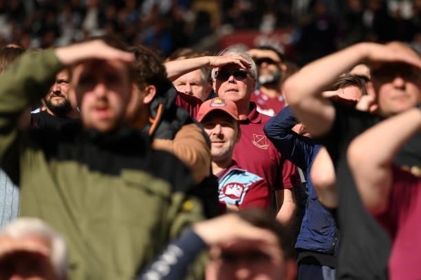 Fans shield their eyes from the sun during the Premier League match between West Ham United and Brentford at London Stadium on October 03, 2021 in...