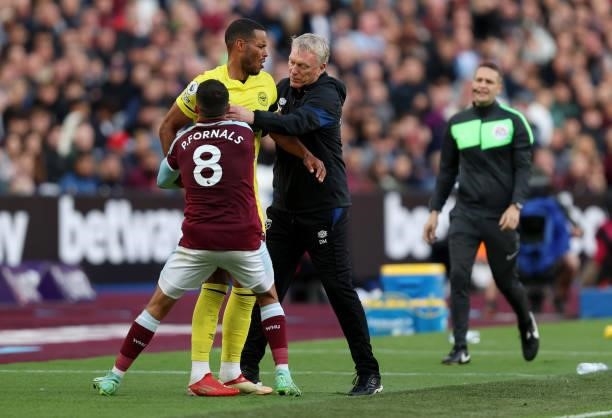 Mathias Zanka Joergensen of Brentford holds onto the ball despite the efforts of David Moyes, Manager of West Ham United and Pablo Fornals during the...