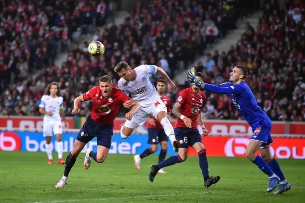 Milik of Olympique de Marseille jumps for the ball between Sven Botman and Ivo Grbic of Lille OSC during the Ligue 1 Uber Eats match between Lille...
