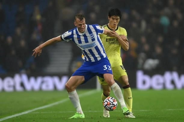 Dan Burn of Brighton & Hove Albion is challenged by Takehiro Tomiyasu of Arsenal during the Premier League match between Brighton & Hove Albion and...