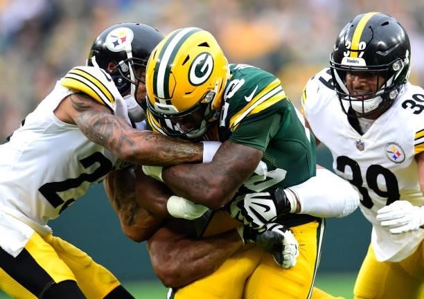 Dillon of the Green Bay Packers is tackled by Joe Haden and Minkah Fitzpatrick of the Pittsburgh Steelers during the first quarter at Lambeau Field...