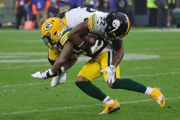 Najee Harris of the Pittsburgh Steelers is brought down by Jaire Alexander of the Green Bay Packers during a game at Lambeau Field on October 03,...