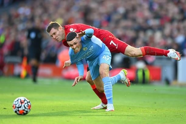 James Milner of Liverpool fouls Phil Foden of Manchester City for which he receives a yellow card during the Premier League match between Liverpool...