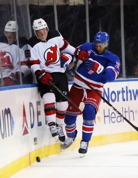 Fabian Zetterlund of the New Jersey Devils is checked into the boards during the first period by K'Andre Miller of the New York Rangers during a...