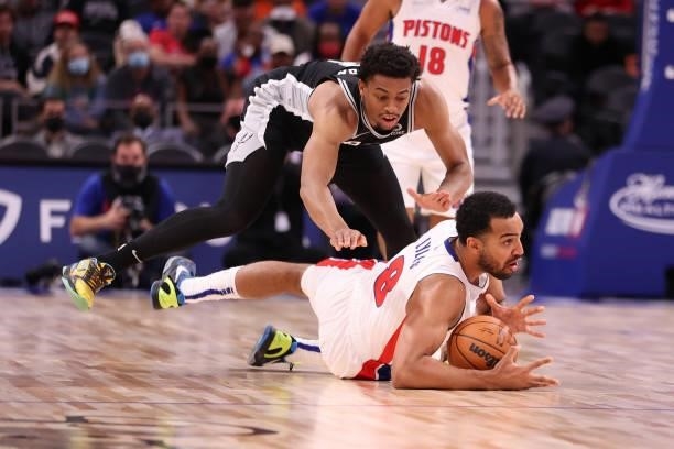 Trey Lyles of the Detroit Pistons dives for the ball in front of Keldon Johnson of the San Antonio Spurs during a preseason game at Little Caesars...