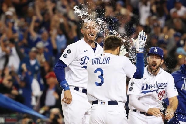 Chris Taylor of the Los Angeles Dodgers celebrates with Cody Bellinger and Steven Souza Jr. #18 after his walk off two-run home run in the ninth...