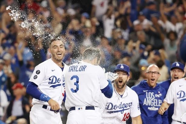 Chris Taylor of the Los Angeles Dodgers celebrates with Cody Bellinger and Steven Souza Jr. #18 after his walk off two-run home run in the ninth...