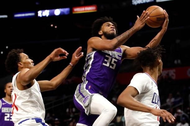Marvin Bagley III of the Sacramento Kings drives to the basket against George King and Keon Johnson of the Los Angeles Clippers during the fourth...