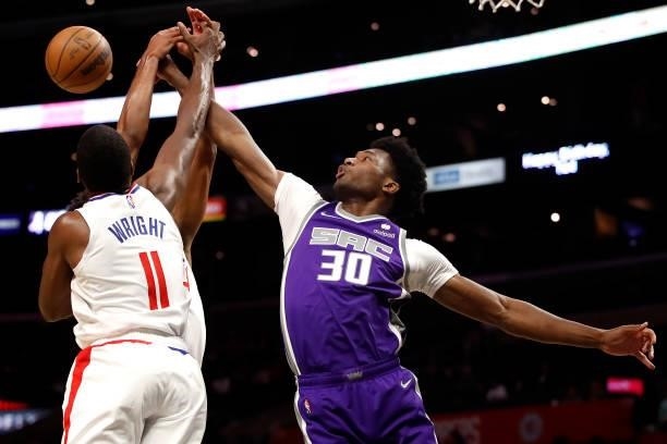 Damian Jones of the Sacramento Kings fights for the ball against Keon Johnson and Moses Wright of the Los Angeles Clippers during the fourth quarter...