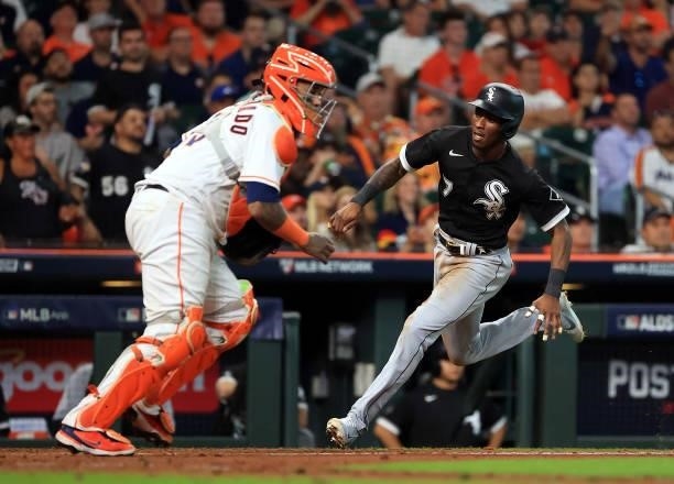 Tim Anderson of the Chicago White Sox slides safely into home to score past catcher Martin Maldonado of the Houston Astros during the 8th inning of...