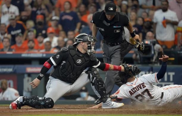 Jose Altuve of the Houston Astros slides home safely around the tag of Yasmani Grandal of the Chicago White Sox in the third inning during Game One...