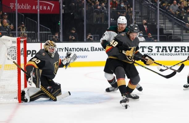 Peter Diliberatore of the Vegas Golden Knights controls the puck against Lawson Crouse of the Arizona Coyotes as Robin Lehner of the Golden Knights...