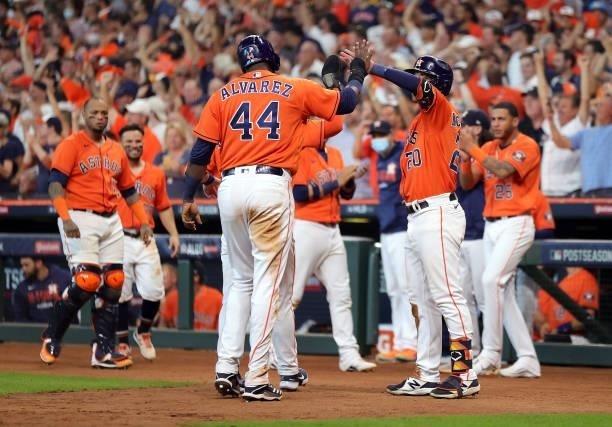 Yordan Alvarez of the Houston Astros is congratulated by teammates after scoring on a double hit by Carlos Correa during the 7th inning of Game 2 of...