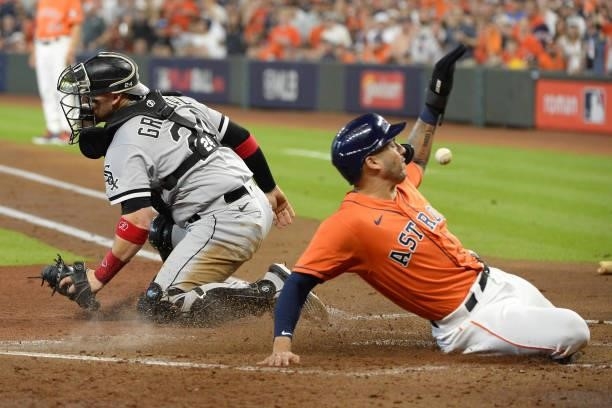 Carlos Correa of the Houston Astros slides home safely as the ball skips by Yasmani Grandal of the Chicago White Sox in the second inning of Game Two...