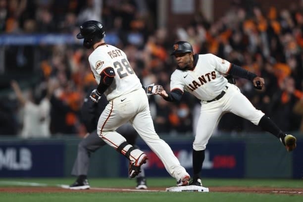 Buster Posey of the San Francisco Giants celebrates with first base coach Antoan Richardson after hitting a two-run home run off Walker Buehler of...