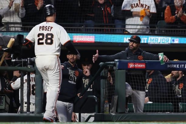 Buster Posey of the San Francisco Giants high fives manager Gabe Kapler after hitting a two-run home run off Walker Buehler of the Los Angeles...